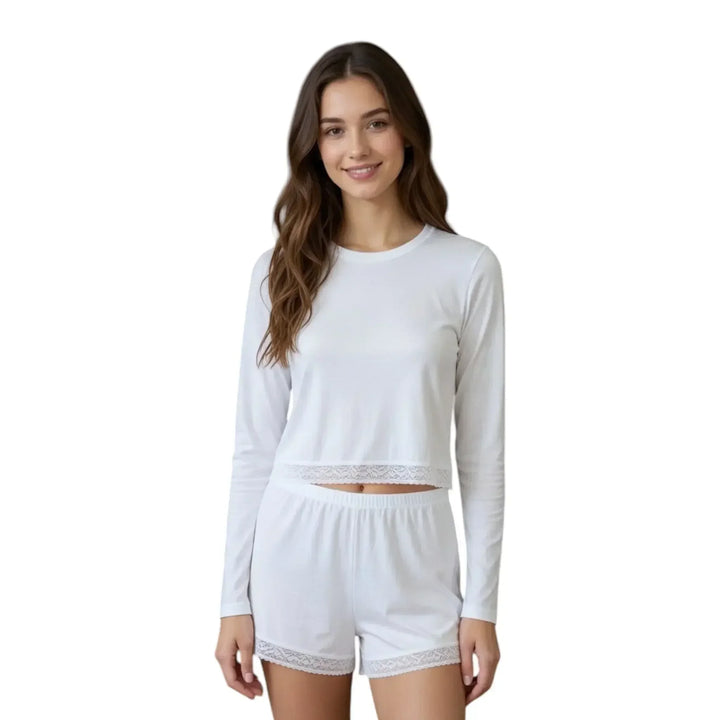 Woman wearing white long sleeve loungewear set with lace trim, standing against white background.